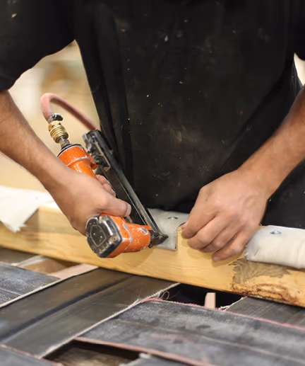 Monteur fixiert Stoffe an einer Holzleiste mit Hilfe einer Druckluftpistole.